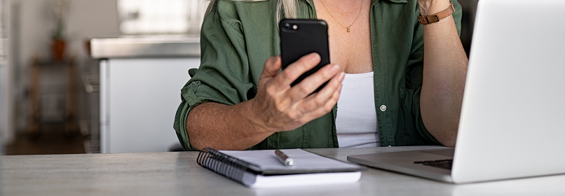 Pessoa conferindo pagamentos de IPTU no celular e no notebook